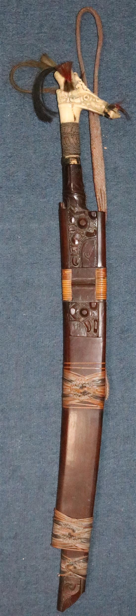 A Dayak stag horn-handled Mandau (head-hunters sword), wood scabbard, late 19th / early 20th century, total length 78.5cm (30.9in.)